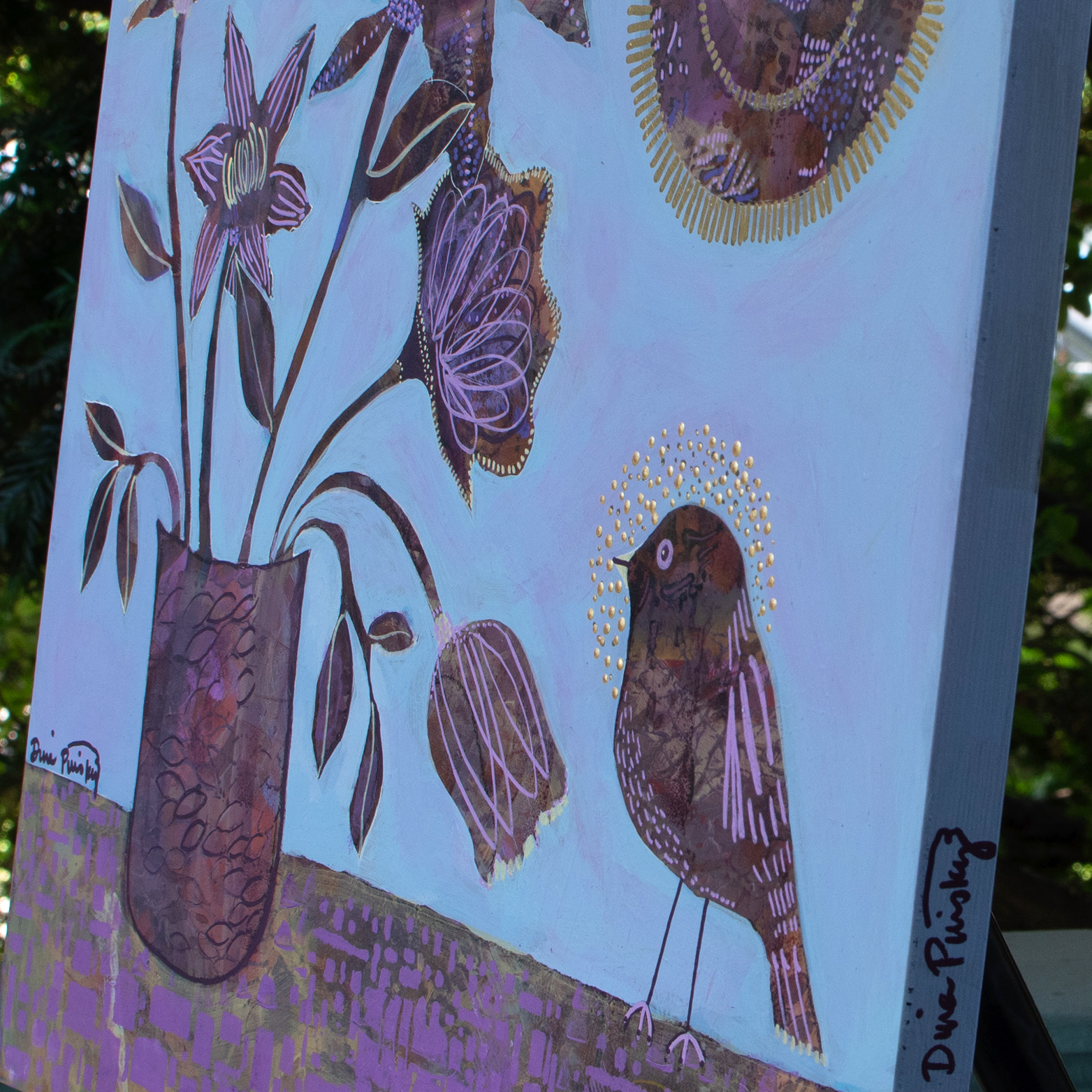 close up of edge of cradled wood panel with acrylic painting, abstract still life with whimsically rendered flowers in a vase on a table where a bird perches and an abstract sun in the top right corner. organic textures and marks within the elements on a periwinkle background. metallic gold paint embellishments. signed by artist dina pinsky on the edge of canvas and front. color palette of purples, browns, golds. 